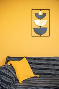a yellow wall with a yellow pillow and a picture at Sirius House in Mytilinioí