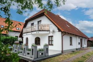 a white house with a balcony on top at Ferienhaus MeerGenerationen in Ueckeritz