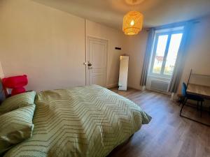 a bedroom with a bed and a desk and a window at Maison de la Gour MELLE in Melle