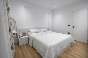 a white bedroom with a bed and a mirror at Dior Apartment in Vlorë