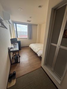 a small bedroom with a bed and a window at ホテル土浦神立ヒルズ in Tsuchiura