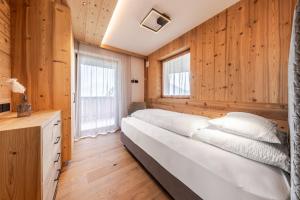 a bed in a room with wooden walls and windows at Chalet Esther in Longega