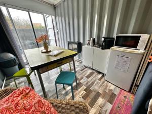 a room with a kitchen with a table and a refrigerator at Séjour insolite dans un Container aménagé à Berck avec Borne d'arcade et Babyfoot in Berck-sur-Mer