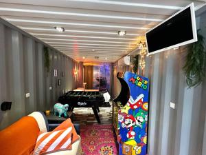 a living room with a television and a room with a bed at Séjour insolite dans un Container aménagé à Berck avec Borne d'arcade et Babyfoot in Berck-sur-Mer