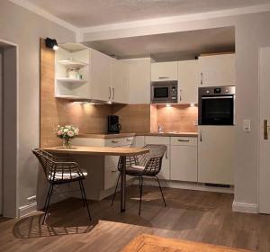 a kitchen with white cabinets and a table and chairs at Golfresidenz Landidyll B 107 in Grömitz
