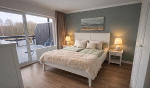 a bedroom with a large bed and a balcony at Golfresidenz Landidyll B 107 in Grömitz +25 photos