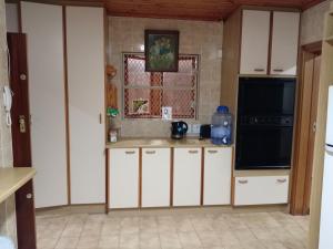 a kitchen with white cabinets and a black microwave at The Victorian Villa in Chintsa
