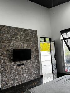 a bedroom with a tv on a brick wall at 22 apartments in Kalapaluwawa
