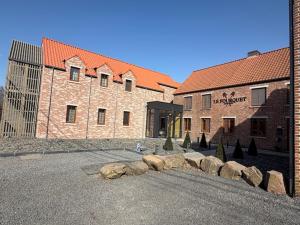 a large brick building with rocks in front of it at Le Fourquet Blaugies - Hôtel & restaurant in Dour