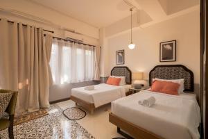 a bedroom with two beds and a window at Chinoir Boutique Phuket Town in Phuket