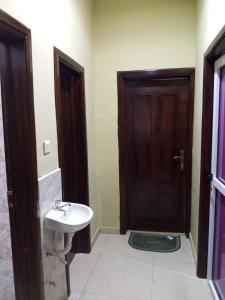 a bathroom with a sink and a wooden door at Eldu Villa in Kokrobite +11 photos