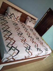 a bed with white sheets and red and black patterns at Eldu Villa in Kokrobite