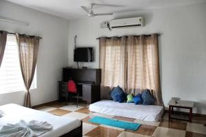 a bedroom with two beds and a tv and a window at Comfort Nest in Coimbatore