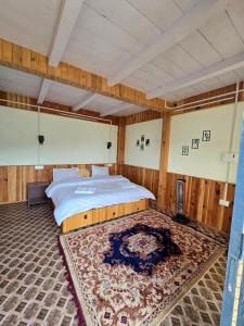 a bedroom with a large bed and a rug at The Ridge Cottages - Sainj Valley in Sainj