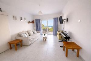 a living room with a white couch and a piano at Two BR Sea View with Balcony and Pool Paphos in Khlorakas