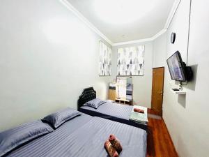 a bedroom with two beds and a flat screen tv at Ministry Homestay in Yogyakarta