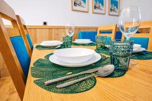 a wooden table with plates and silverware on it at Szmaragdowa Przystań - apartament z parkingiem blisko Parku Zdrojowego i Tężni in Busko-Zdrój +14 photos