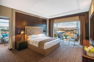 a bedroom with a bed and a view of a city at The Biltmore Tbilisi Hotel in Tbilisi City