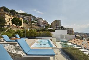 a patio with chairs and a swimming pool on top of a building at De Bonart Naples, Curio Collection By Hilton in Naples