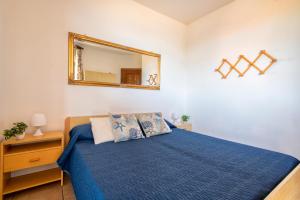 a bedroom with a blue bed and a mirror at Dimore Dell'Isola Rossa in Isola Rossa