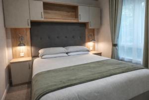 a bedroom with a large bed with two lamps at Cheviot Pines Northumberland in Swarland
