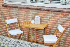 a table and two chairs sitting next to a brick wall at Sotto Terra in Katwijk aan Zee