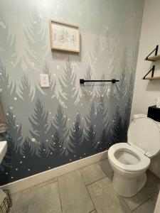 a bathroom with a toilet and a wall with a christmas tree mural at Mountain bike Ski Eville Mecca in Ellicottville +26 photos