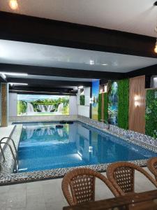 a large swimming pool with chairs in a building at MUXSIN s in Bukhara