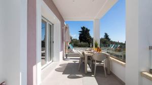 a patio with a table and chairs on a balcony at Villa Filothea with Jacuzzi & SV by CorfuEscapes in Spartýlas