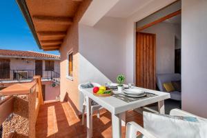 a white table with a bowl of fruit on a balcony at Dimore Dell'Isola Rossa in Isola Rossa
