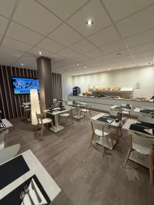 a restaurant with tables and chairs and a tv at Confidence Hotel Europa in Cento