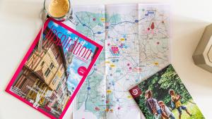 a map and a cup of coffee next to a book at Au petit détour Confort in Rolampont