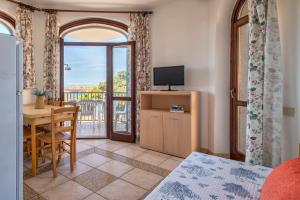 a living room with a dining table and a balcony at Dimore Dell'Isola Rossa in Isola Rossa
