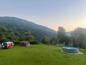a field with two tents and a swimming pool at Baumgartnerhof Arriach - Urlaub am Bauernhof in Arriach
