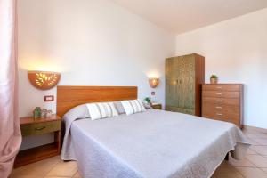 a bedroom with a white bed and a dresser at Verande Tanca Torre in Isola Rossa