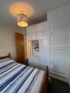 a bedroom with a bed with a blue and white stripes at Caban Caru 2 in Tywyn