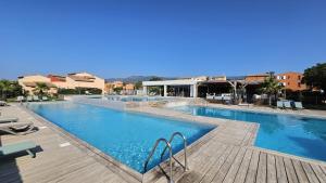 a large swimming pool with a wooden deck at Valduccina - T3 avec terrasse et piscine, proche de la plage in Lecci