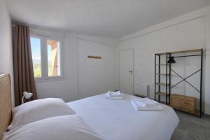 a white bedroom with a bed and a window at Valduccina - T3 avec terrasse et piscine, proche de la plage in Lecci