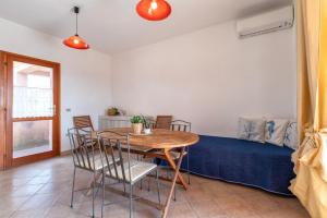 a dining room with a table and chairs and a couch at Verande Tanca Torre in Isola Rossa