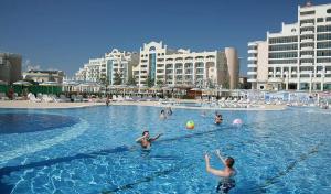 a group of people playing with a ball in a swimming pool at Apartment SunSet rezort - sea wiew in Pomorie