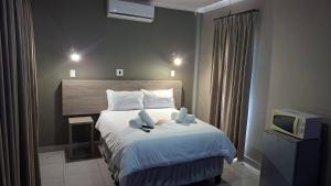 a hotel room with a bed and a tv at Postmasburg Inn in Postmasburg
