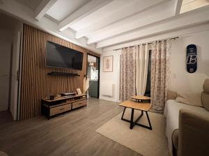 a living room with a couch and a television on a wall at Les Embruns de Tarnos in Tarnos