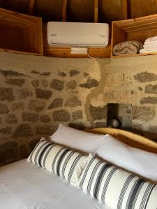 a bed with pillows in a room with a stone wall at Petromilos1920 in Zefiría