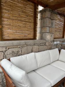 a white couch sitting in front of a stone wall at Petromilos1920 in Zefiría +22 photos