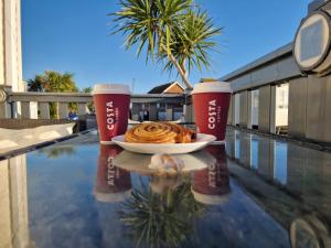 a plate of food on a table next to two cups at Seaside Holiday Home Inside a Resort in Selsey