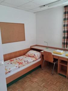 a bedroom with a bed and a desk and a table and a desk at Kolpinghaus Villach in Villach