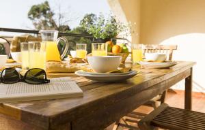 a wooden table with glasses of orange juice and food on it at Vacancéole - Résidence Sognu di Mare in Linguizzetta