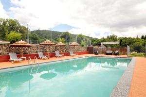 a large swimming pool with chairs and umbrellas at Domaine Le Prieuré in Chaumont-le-Bourg