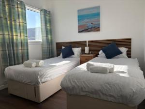 two twin beds in a room with a window at The Ferry Boat Inn in Ullapool