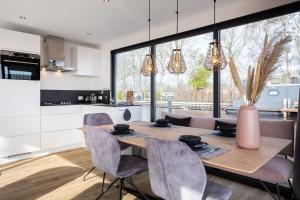 a kitchen and dining room with a wooden table and chairs at de Valreep - Paviljoenwei 4 Offinga in Offingawier +23 photos